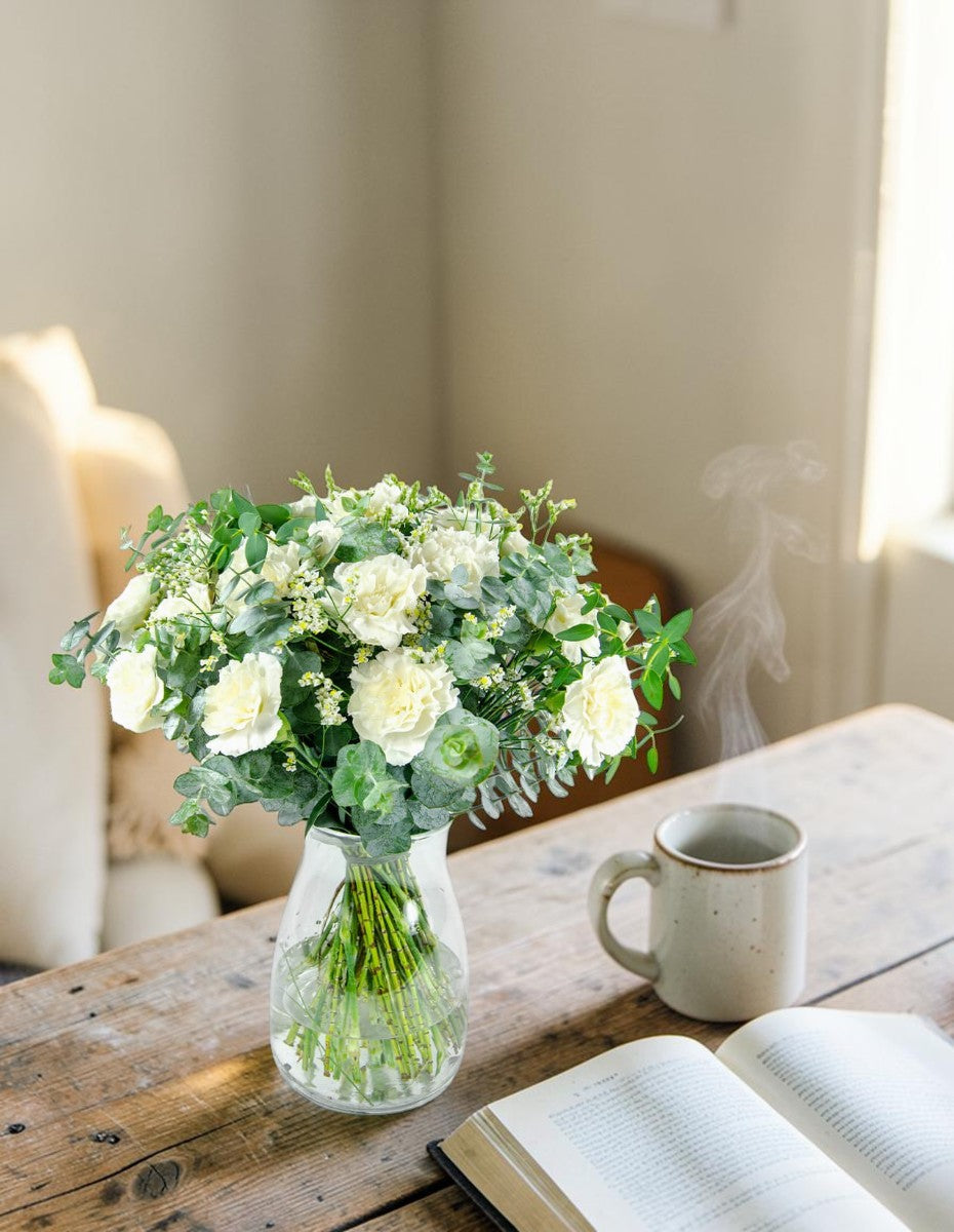 Ramo de claveles blancos en jarrón sobre mesa de madera - Floristería Peregrina Pontevedra